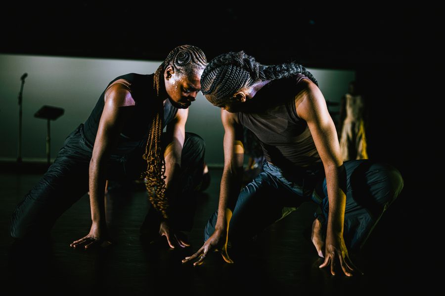 Scènefoto uit de voorstelling Closed Eyes, dansers en tweelingzussen Nathalie en Doris Bokongo Nkumu zittend op handen en knieën.
