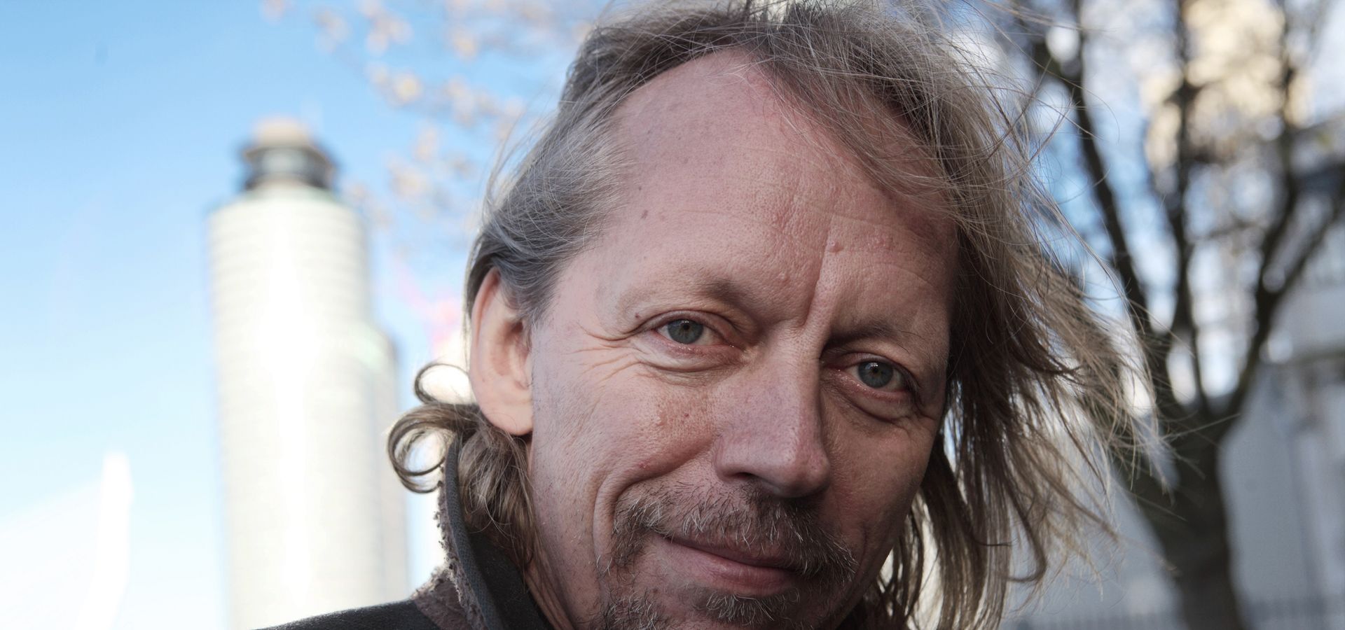 Een op straat gemaakte foto van voormalig Rotterdamse Schouwburg directeur Jan Zoet die zachtaardig in de camera kijkt
