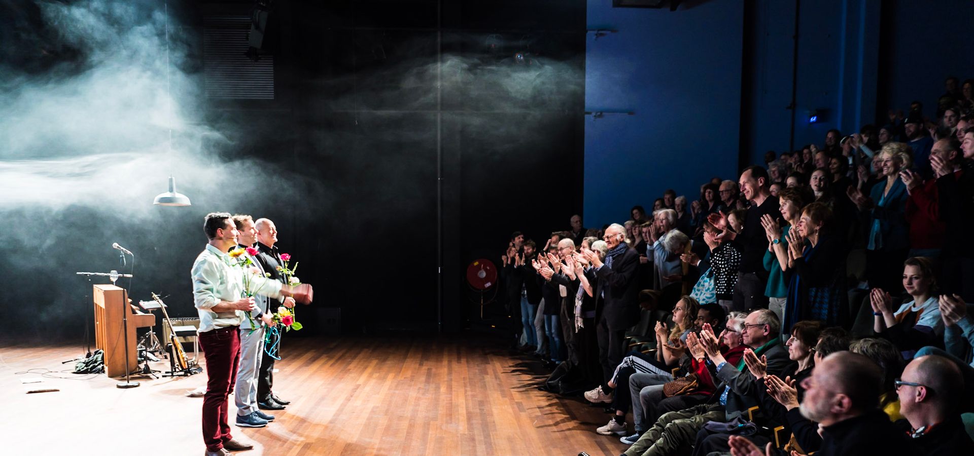 Slotapplaus na een voorstelling in de kleine zaal. De spelers hebben bloemen in hun handen en kijken het publiek in