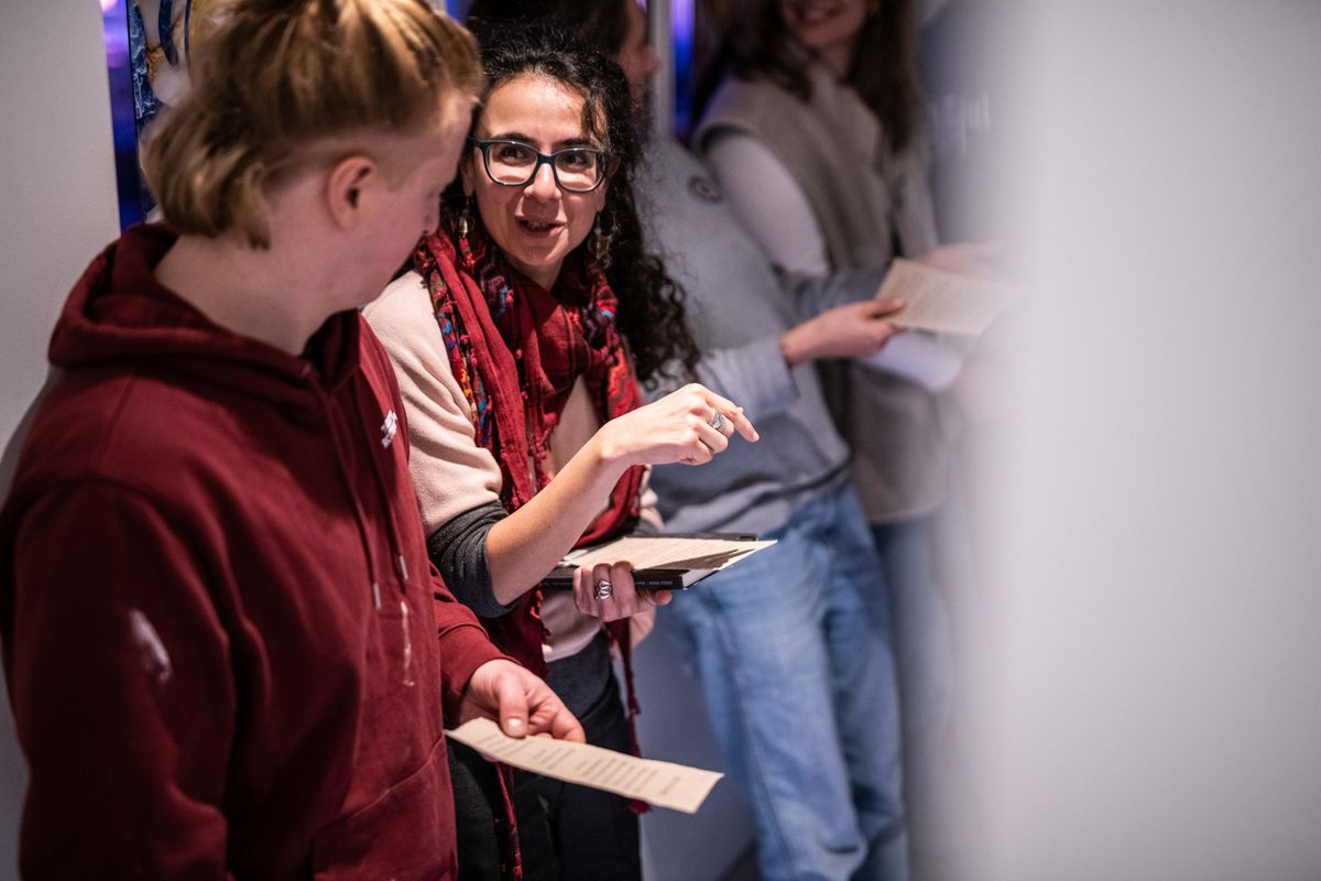 Een groep bezoekers staat samen in gesprek terwijl ze papieren in handen houden.