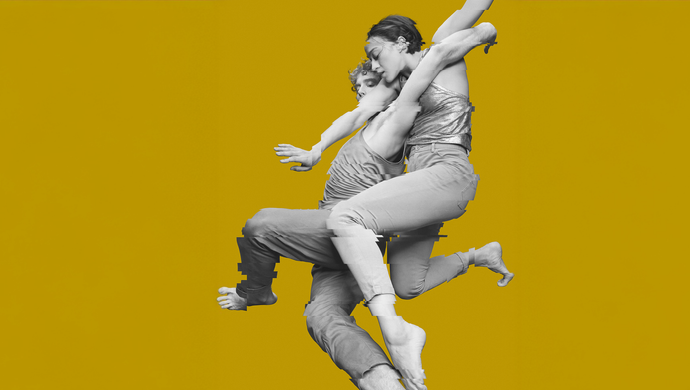Twee dansers verstrengeld en gefotografeerd in zwart wit tegen een oker achtergrond