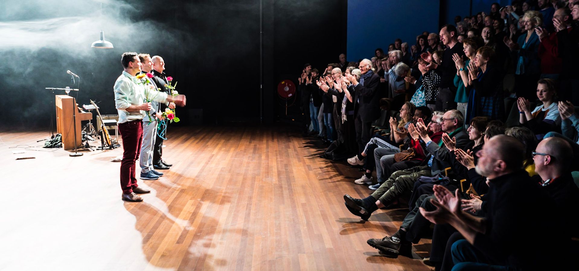 Slotapplaus na een voorstelling in de kleine zaal. De spelers hebben bloemen in hun handen en kijken het publiek in